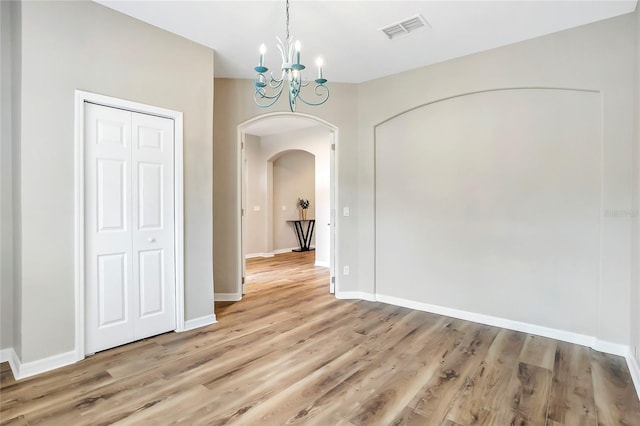 unfurnished dining area with wood-type flooring and a notable chandelier