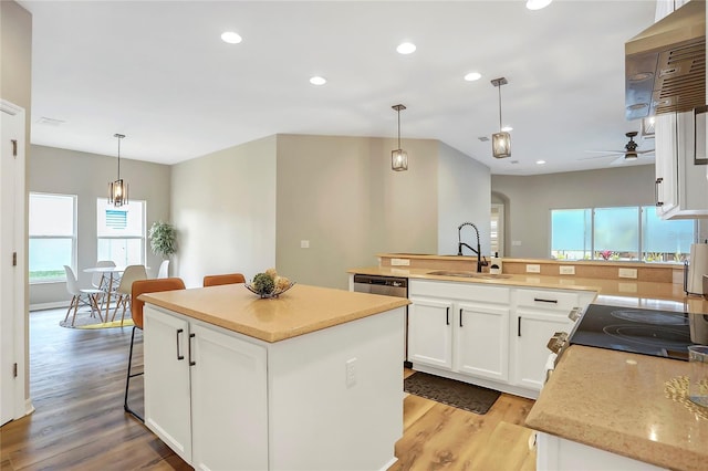 kitchen with sink, white cabinetry, hanging light fixtures, and a kitchen island