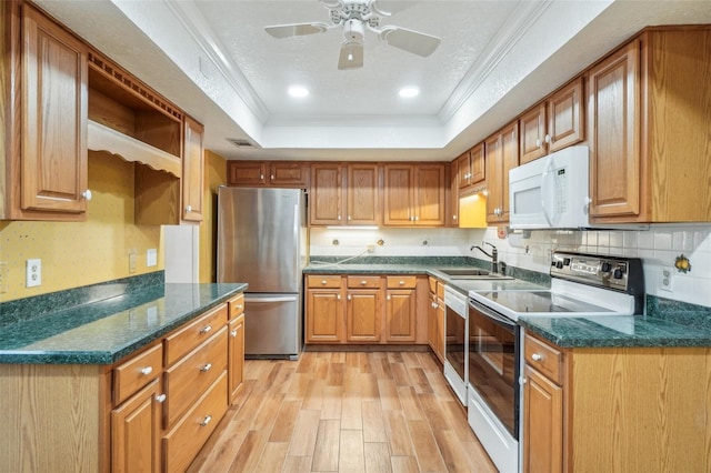 kitchen with white microwave, a sink, electric stove, freestanding refrigerator, and a tray ceiling