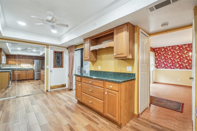 kitchen with visible vents, freestanding refrigerator, a tray ceiling, dark countertops, and crown molding