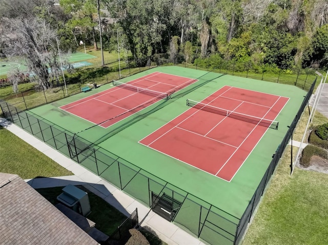 view of sport court with fence and a lawn