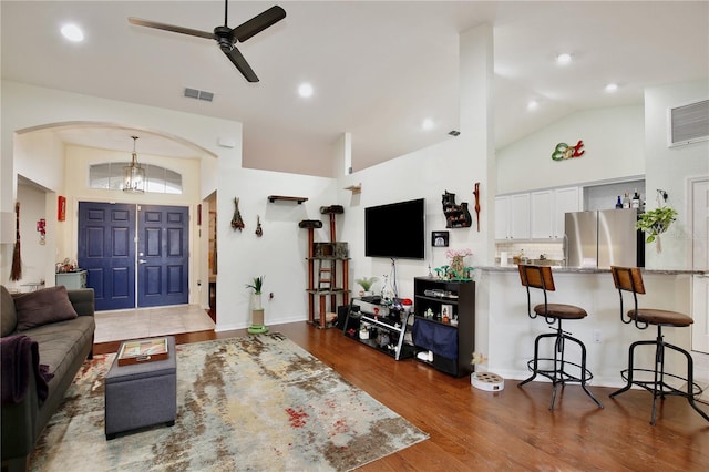 living room featuring dark hardwood / wood-style flooring, high vaulted ceiling, and ceiling fan