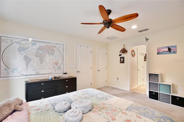 bedroom with multiple closets, light colored carpet, and ceiling fan