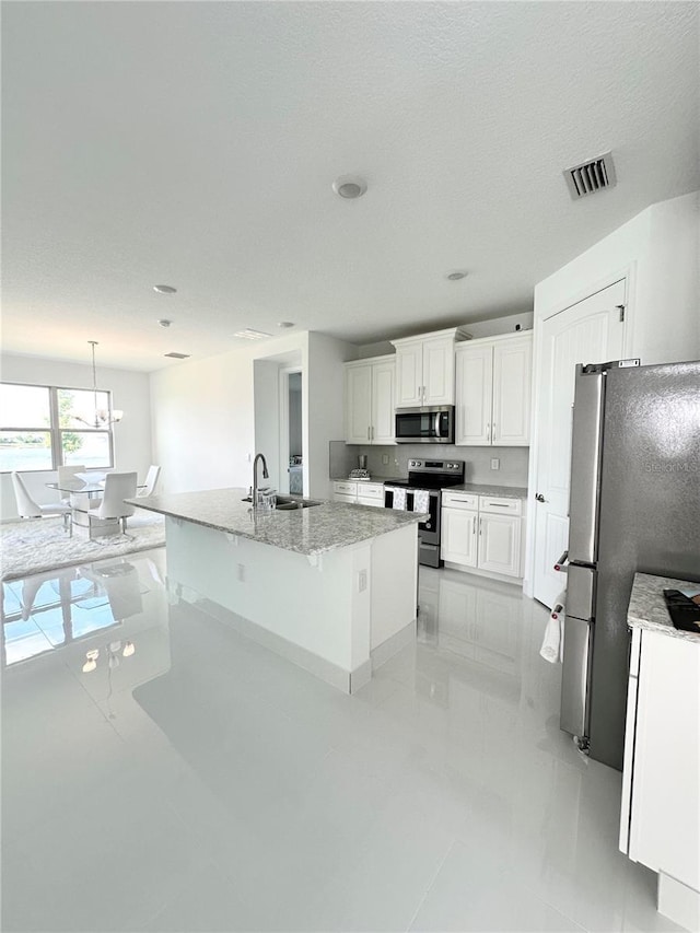 kitchen featuring appliances with stainless steel finishes, white cabinetry, an island with sink, sink, and hanging light fixtures