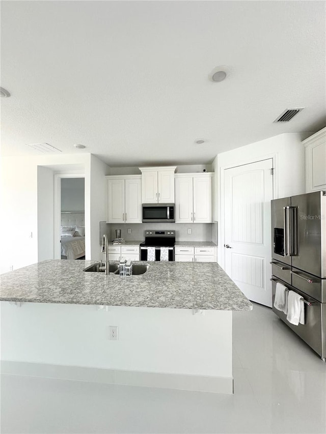 kitchen featuring a large island with sink, white cabinets, appliances with stainless steel finishes, sink, and light tile patterned floors