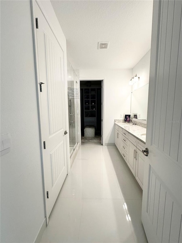 bathroom with vanity, tile patterned floors, an enclosed shower, and a textured ceiling