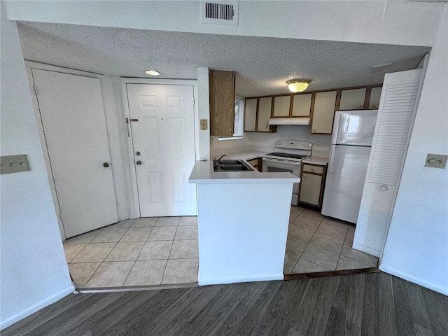 kitchen with sink, light tile patterned flooring, white appliances, and a textured ceiling