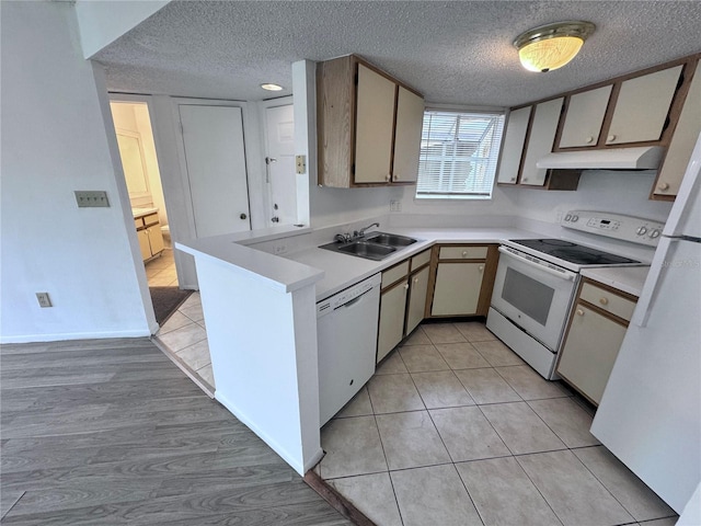 kitchen with sink, white appliances, light tile patterned floors, and a textured ceiling