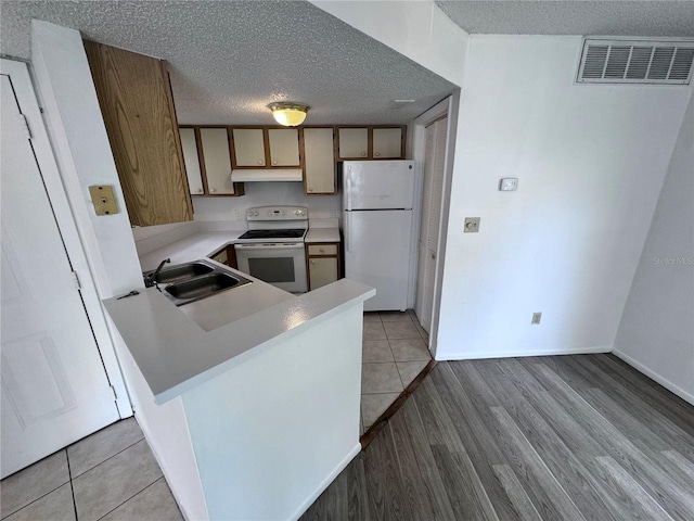 kitchen with white appliances, a textured ceiling, sink, kitchen peninsula, and light tile patterned flooring