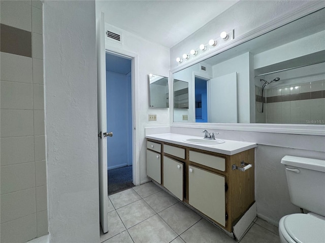 bathroom with vanity, toilet, tiled shower, and tile patterned flooring