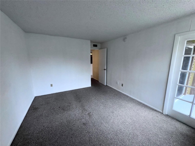 spare room featuring dark colored carpet and a textured ceiling