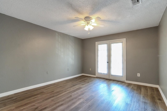 empty room featuring ceiling fan, dark wood-type flooring, a textured ceiling, and french doors