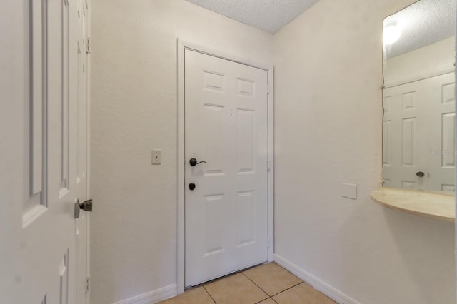 doorway to outside with a textured ceiling and light tile patterned flooring