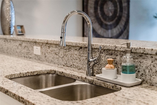 details featuring backsplash, light stone countertops, and a sink