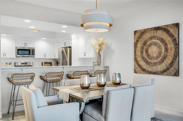 dining room with recessed lighting, light wood-type flooring, and baseboards