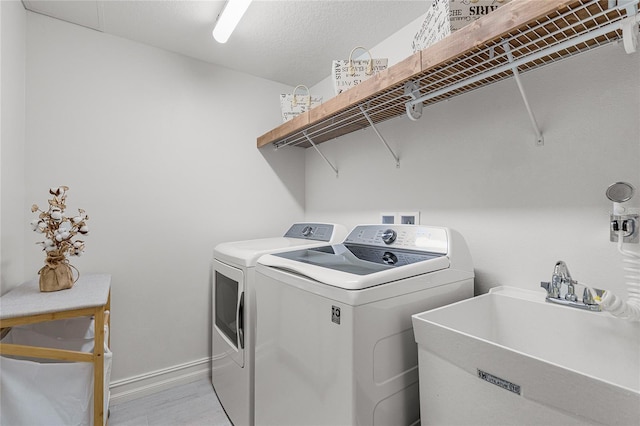 laundry area with laundry area, washing machine and clothes dryer, baseboards, and a sink