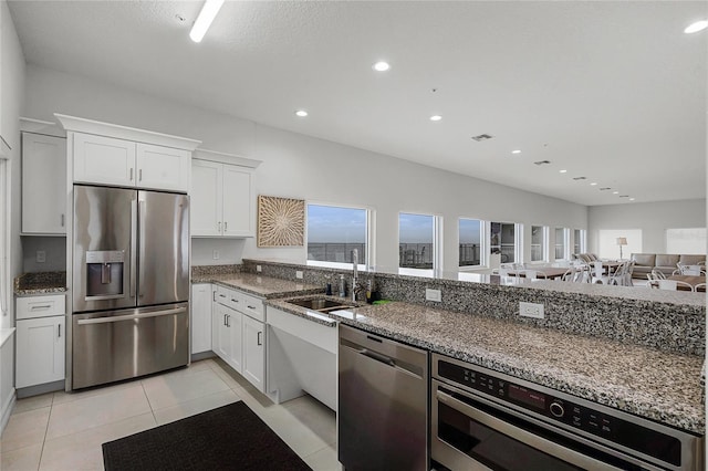 kitchen featuring stone countertops, stainless steel appliances, and a sink