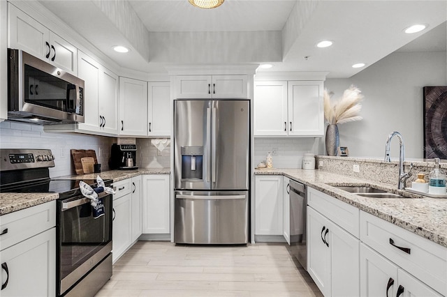 kitchen featuring a sink, stainless steel appliances, light wood-style flooring, and white cabinetry