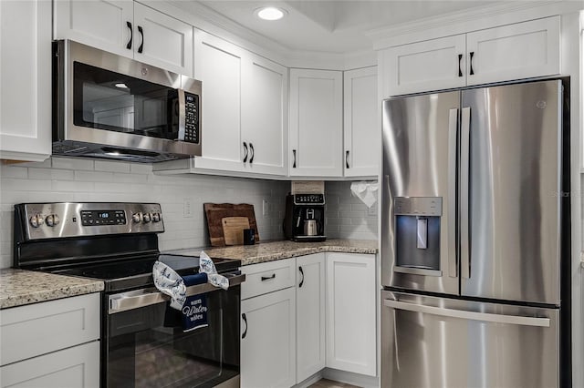 kitchen with white cabinetry, decorative backsplash, light stone counters, and stainless steel appliances