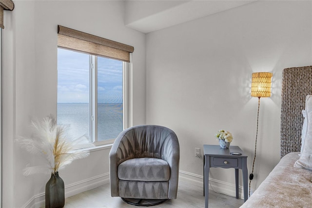 sitting room featuring a water view, baseboards, and wood finished floors