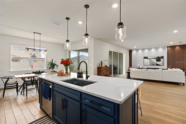 kitchen with blue cabinets, sink, decorative light fixtures, dishwashing machine, and an island with sink