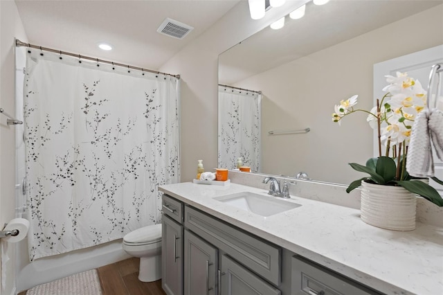 full bathroom featuring vanity, hardwood / wood-style floors, shower / bath combo with shower curtain, and toilet