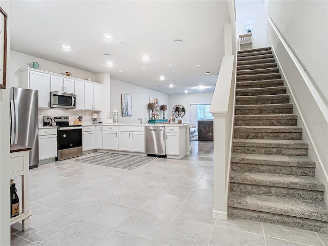 kitchen with light tile patterned flooring, sink, kitchen peninsula, stainless steel appliances, and white cabinets