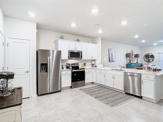 kitchen with white cabinetry, sink, stainless steel appliances, and kitchen peninsula