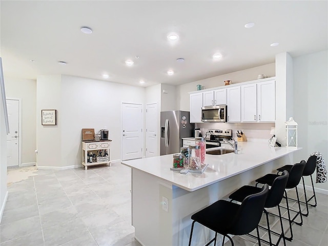 kitchen with stainless steel appliances, a kitchen breakfast bar, kitchen peninsula, and white cabinets