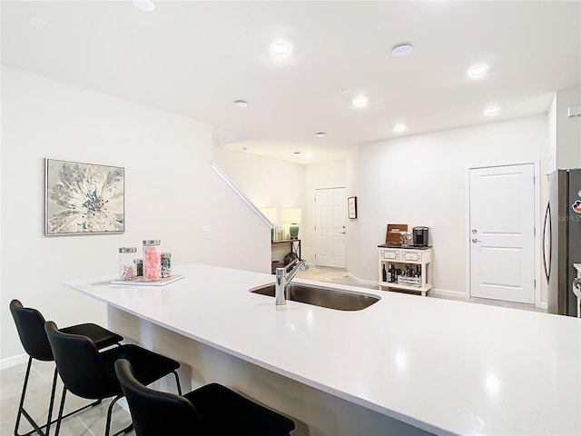 kitchen with sink, stainless steel fridge, kitchen peninsula, and a kitchen bar