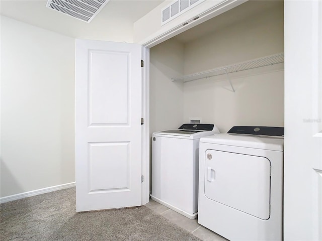 clothes washing area featuring light carpet and washer and dryer