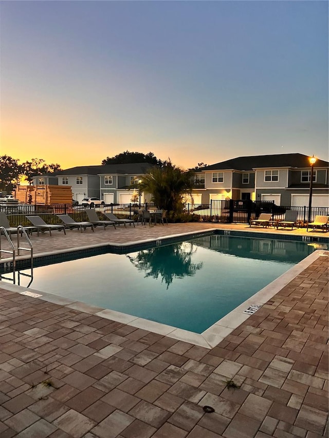 pool at dusk with a patio area