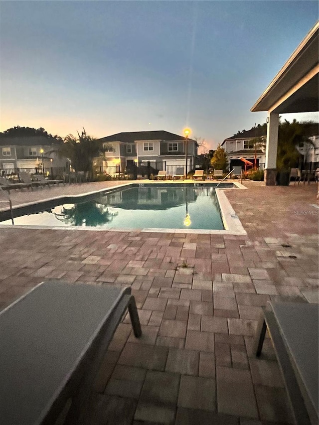 pool at dusk featuring a patio area