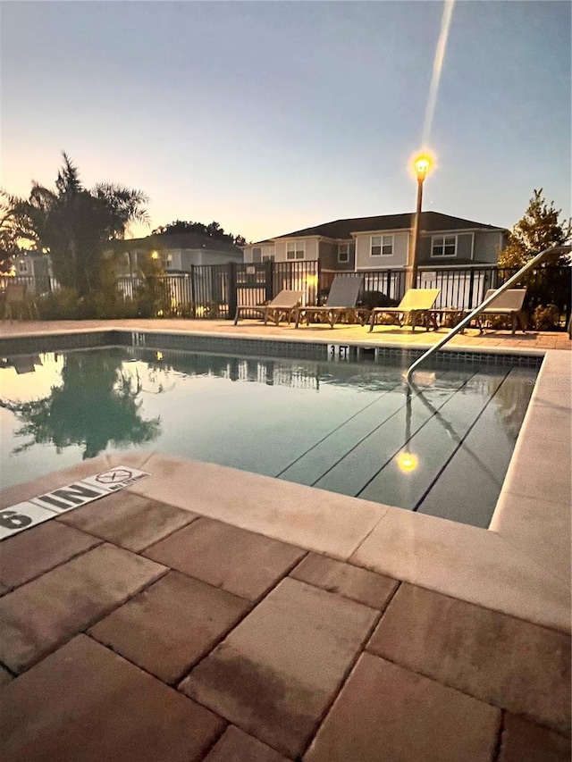 pool at dusk featuring a patio