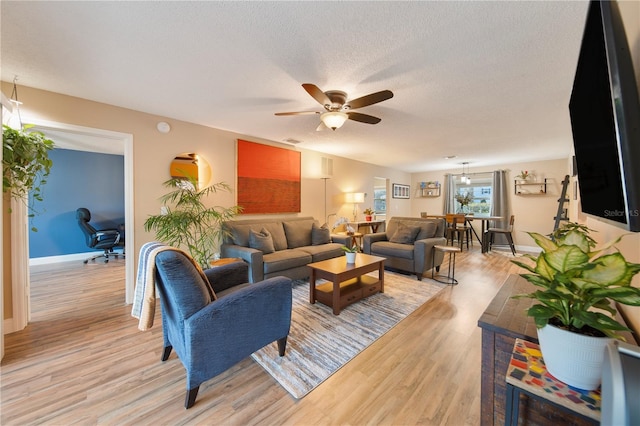 living room featuring a textured ceiling, light hardwood / wood-style floors, and ceiling fan