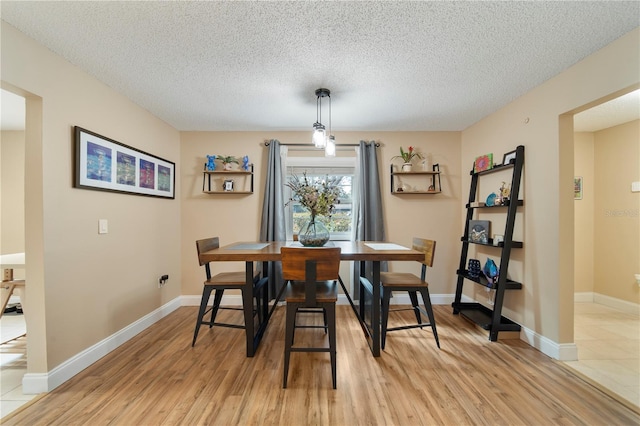 dining area featuring light hardwood / wood-style flooring and a textured ceiling