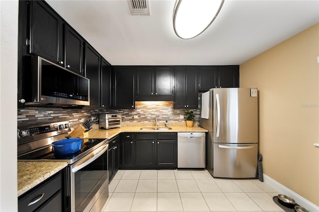 kitchen featuring sink, light tile patterned floors, stainless steel appliances, and light stone countertops