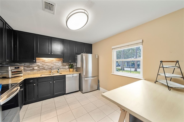 kitchen with appliances with stainless steel finishes, sink, light tile patterned floors, and backsplash