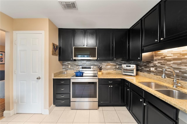 kitchen with sink, decorative backsplash, light tile patterned floors, and appliances with stainless steel finishes