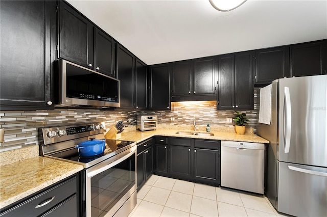 kitchen with tasteful backsplash, sink, light tile patterned floors, light stone counters, and stainless steel appliances