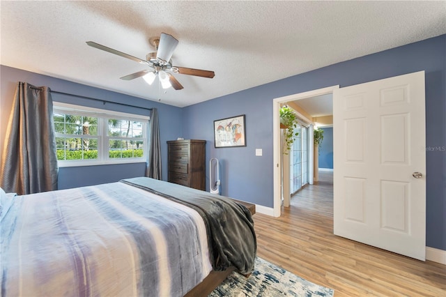 bedroom with a textured ceiling, ceiling fan, and light wood-type flooring