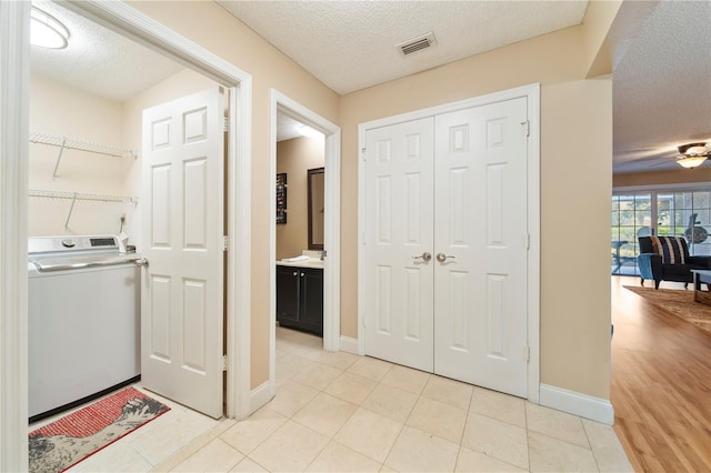 interior space featuring light tile patterned floors, washer / dryer, and a textured ceiling