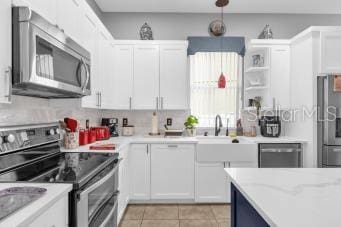 kitchen with sink, light tile patterned floors, white cabinetry, stainless steel appliances, and light stone counters