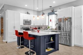 kitchen with white cabinetry, appliances with stainless steel finishes, a kitchen breakfast bar, and a center island