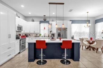 kitchen featuring a kitchen island, appliances with stainless steel finishes, pendant lighting, and white cabinets