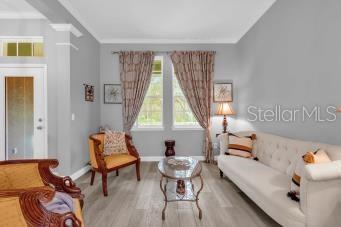 sitting room with crown molding and light wood-type flooring