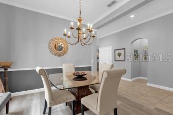 dining area with crown molding, an inviting chandelier, and light wood-type flooring