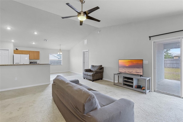 carpeted living room with ceiling fan, plenty of natural light, and vaulted ceiling