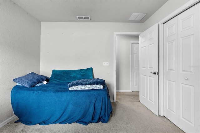 carpeted bedroom with a textured ceiling and a closet