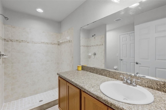 bathroom featuring tiled shower, vanity, and tile patterned flooring